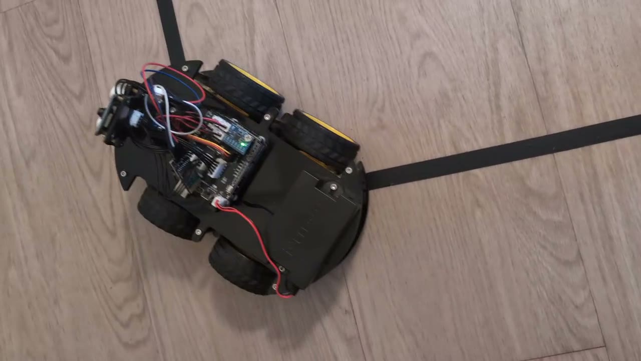 The Elegoo V4 robot car seen from above, driving along a strip of black tape on a wood floor